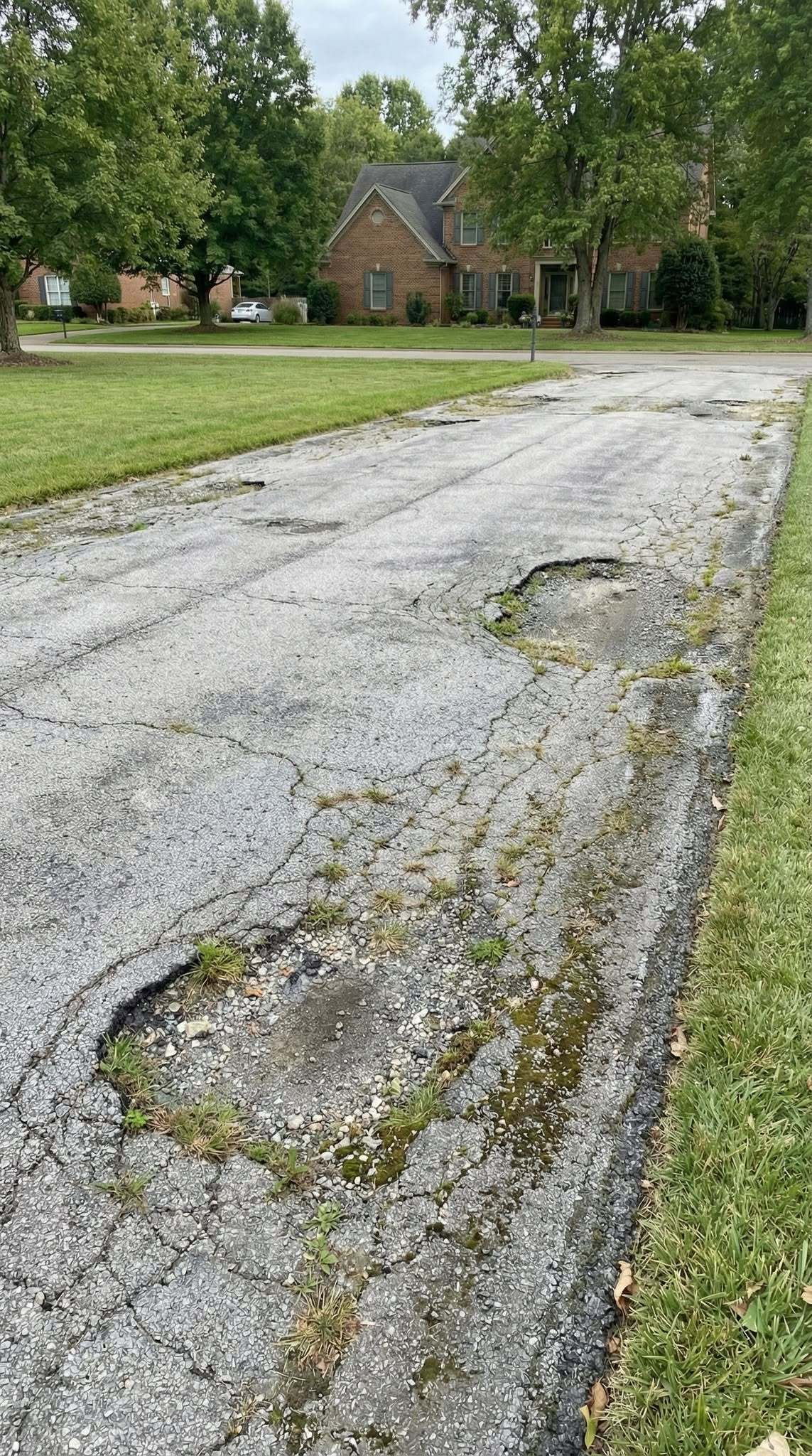 Driveway before: cracked, faded, and potholed asphalt