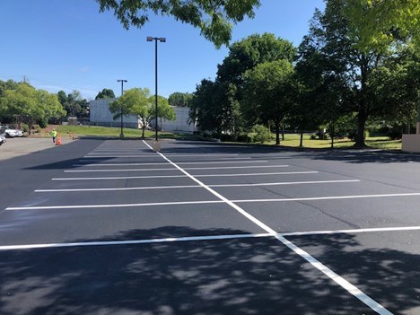 Commercial parking lot freshly sealcoated to a deep glossy black finish with new stripes